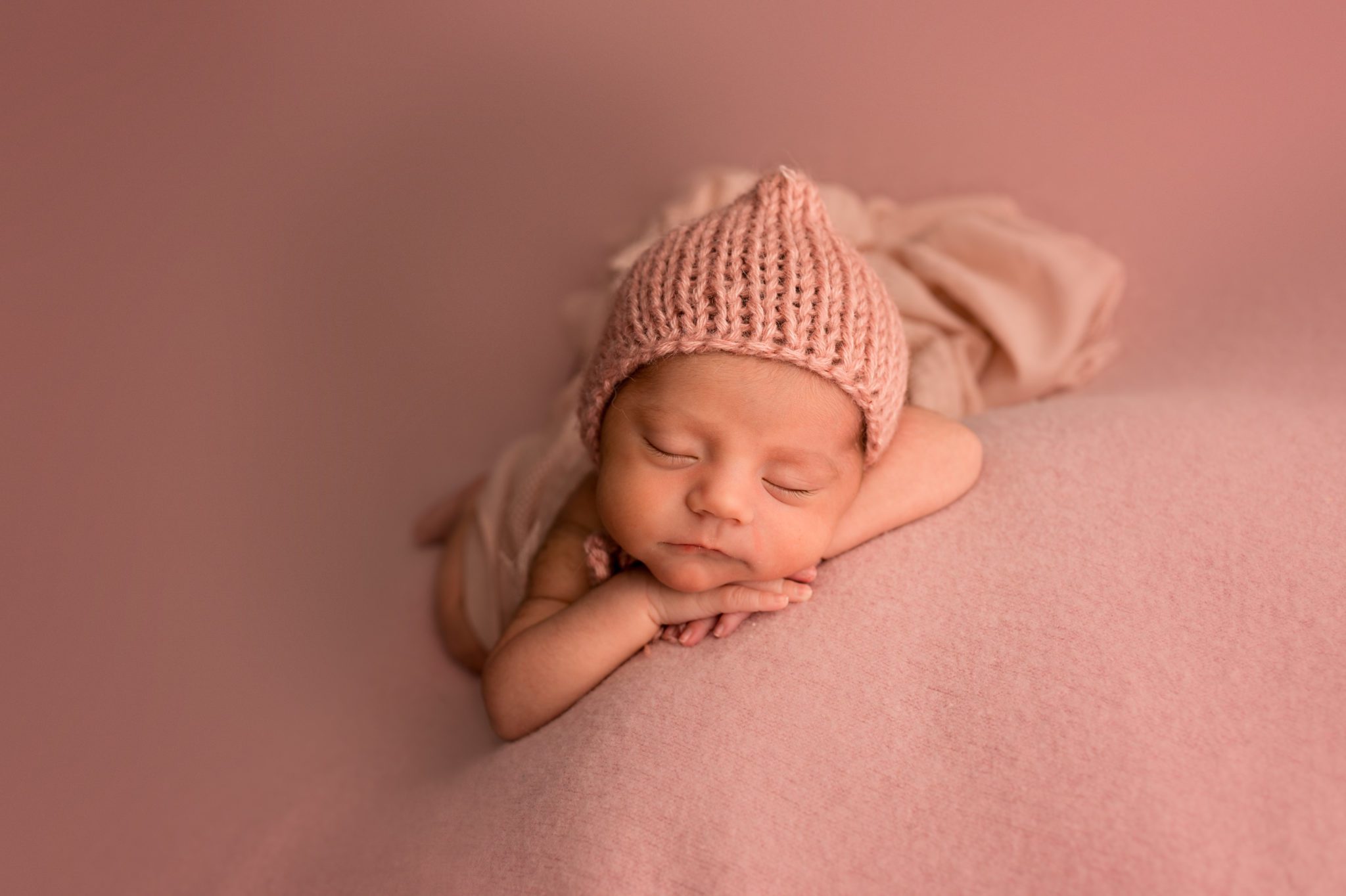 Newborn Baby girl on pink backdrop with pink hat in Loveland Photo studio
